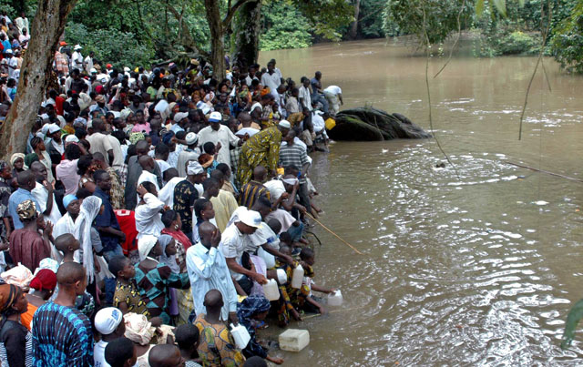 People gather at the Osun sacred river to collect water during the annual worship festival of a river goddess in Osogbo